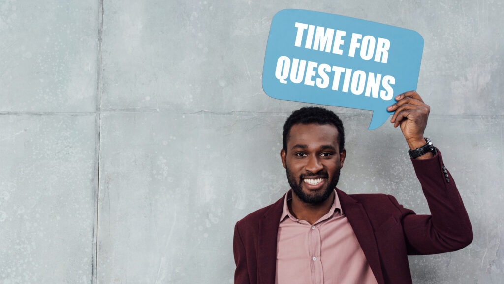 Man in business casual holding a sign that says time for questions.